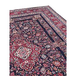 Persian Hamadan indigo ground carpet, the field decorated with central rectangle and outer band, overall floral pattern with cusped central medallion and surrounding leafy branches with palmettes, the border with scrolling branches decorated with further palmettes, within floral pattern guard stripes