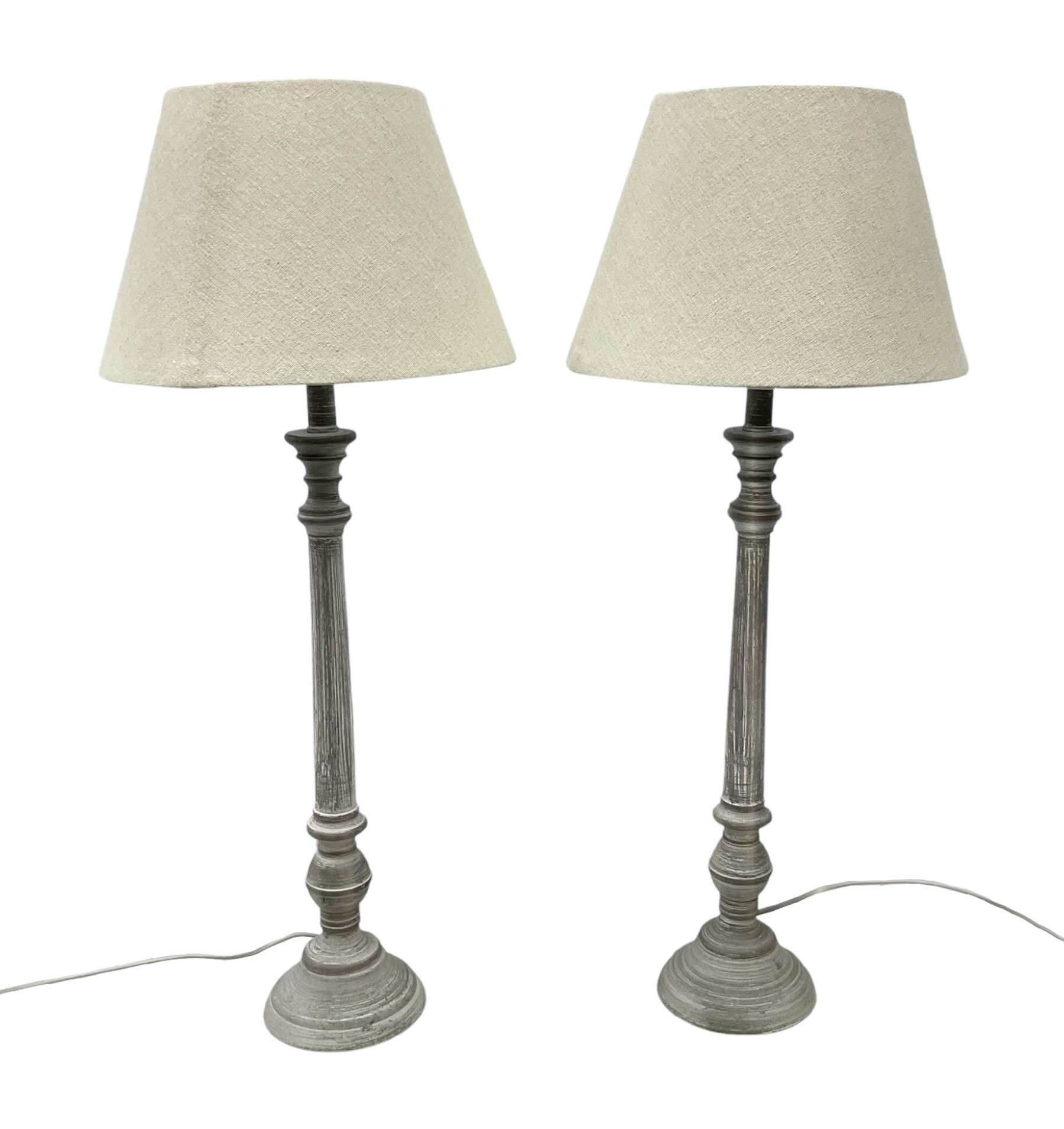 Pair of composite grey washed table lamps with a slender column upon a circular foot with natural linen shades