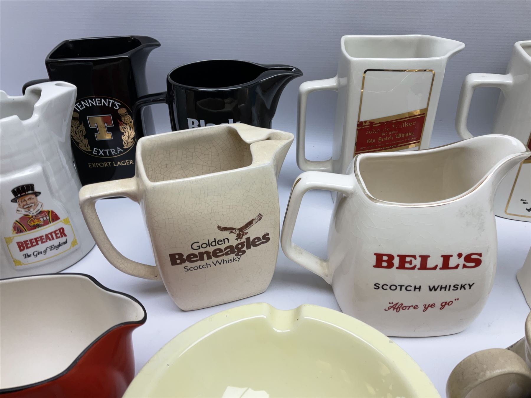 Collection of ceramic pub jugs and ashtrays, including Senior Service ashtray, Bell's old scotch whiskey ashtray,Arthur Bell & sons jug, Beefeater gin jug, two Black and White scotch whiskey jugs, etc    