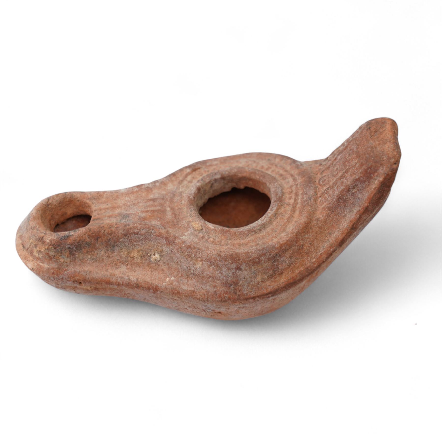 A group of four Byzantine terracotta oil lamps - Eastern Mediterranean, c.5th-7th century AD, comprising a group of mould-made slipper-form oil lamps, each with a rounded body, large central filling hole, and a short to elongated nozzle; including one with fine radiating linear decoration, and another preserving ancient use with traces of oil and wick residue within the burnished interior; together with a Crusader-period terracotta oil lamp (c.12th-13th century AD) of angular form with recessed panel decoration and a pierced handle moulded as a stylised animal head
Provenance: By the vendor’s repute, acquired/collected in the Middle East (Dead Sea area/Syria) in the 1960s