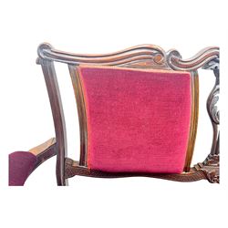 Late Victorian stained beech framed sofa, the backrests, seat and padded arms upholstered in deep red fabric, carved crest rail with scroll and foliate motifs supported by carved uprights, on cabriole supports with leaf carvings terminating in castors