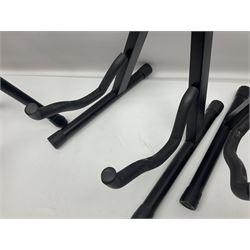 Four folding tubular guitar stands, two by RockJam; and folding tubular saxophone stand (5)