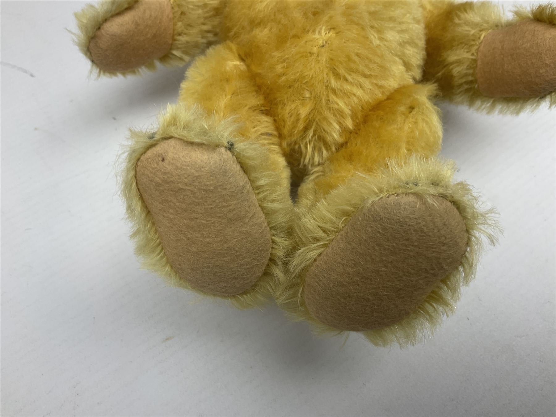 Steiff teddy bear with golden plush body, revolving head, applied eyes, vertically stitched nose and mouth and jointed limbs; button to left ear H26cm; and two other Steiff teddy bears, each with open mouth and button with tag to left ear (3)
