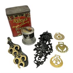 20th century cast iron wall bracket/pocket, modelled as a female mask with acanthus support, together with a silver plated tobacco jar with pipe finial to the cover, toffee tin detailed 'Riley's Toffee Rolls', and small group of brass horseshoes, in one box