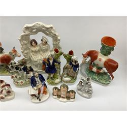 Collection of  Victorian Staffordshire and Staffordshire style pottery, including a man seated writing a letter H18cm, pair of lovers under an arbour H35.5cm, spill vase depicting a cow and calf on a naturalistic base, a pair of spaniels on a cushioned base etc. 