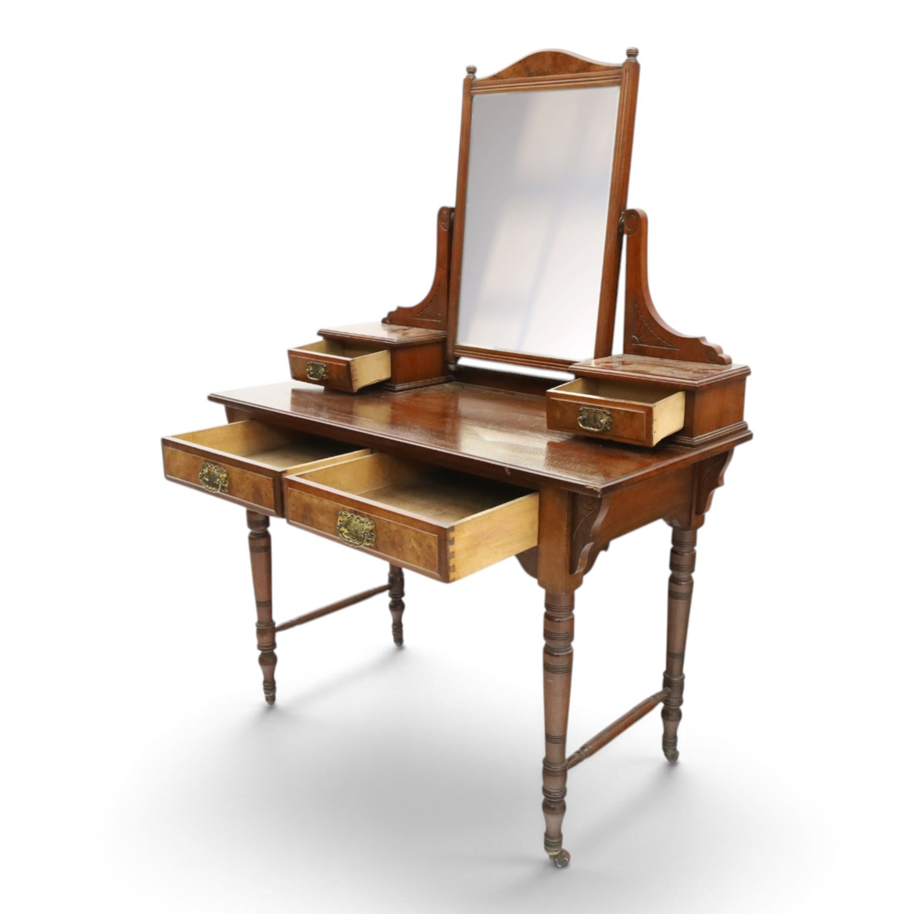 Late Victorian figured walnut and mahogany dressing table, raised swing-mirror back over trinket drawers, fitted with two drawers with brass Aesthetic Movement handles, on ring-turned supports with ceramic castors