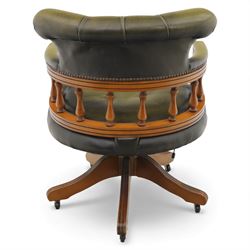 Late 20th century swivel captain’s desk chair, green buttoned vinyl upholstered back and seat with brass stud edging, the spindle gallery over a rotating base with five splayed supports on castors