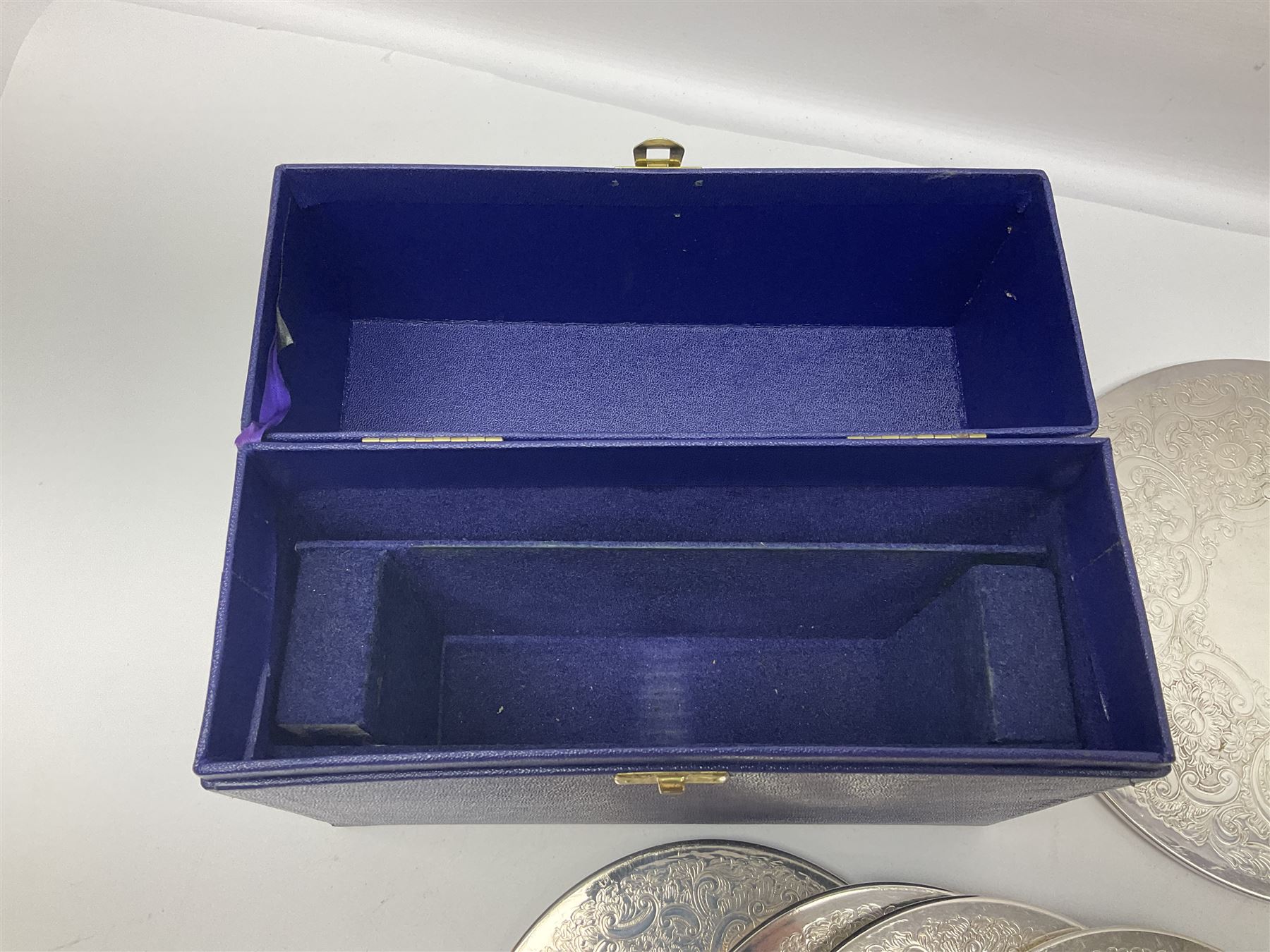 Set of eight silver plated placemats, each of circular form with engraved scroll and floral decoration, including two larger and six smaller examples, largest D23cm, in fitted case 