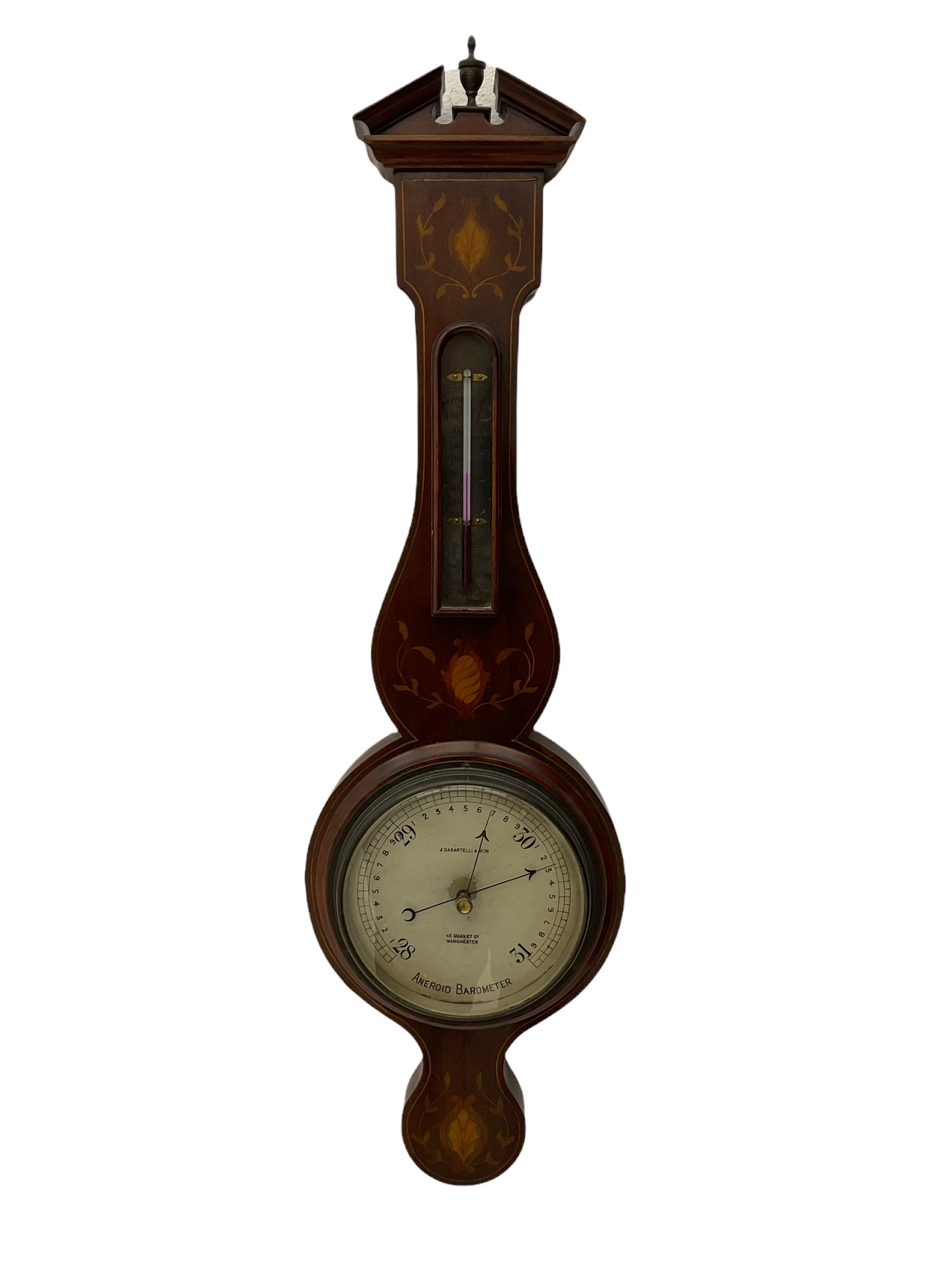 A compact Edwardian Aneroid barometer in a  Regency “Sheraton style”case, broken pediment with finial and rounded base, mahogany veneered with satinwood stringing to the edge and panels of coloured and shaded conch shell and leaf inlay enclosed within entwined leaves, with a six inch dial recording barometric air pressure from 28 to 31 inches in fifths of an inch, steel indicating hand and brass recording hand, dial inscribed “J Casartelli & Son, 43 Market Street, Manchester”, with a flat bevelled glass and brass bezel, glazed arched topped thermometer box with a spirit thermometer and silvered register recording the temperature in degrees Fahrenheit.
*J Carsatelli & Son (1896-1925) A partnership between Joseph Lewis and his son Joseph Henry. The elder Joseph died in 1900 and the son carried on the business until his death in 1925.  
