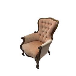 Victorian walnut framed armchair, shaped back with carved and scrolled arm terminals, upholstered in buttoned pale pink fabric, raised on cabriole supports terminating in castors