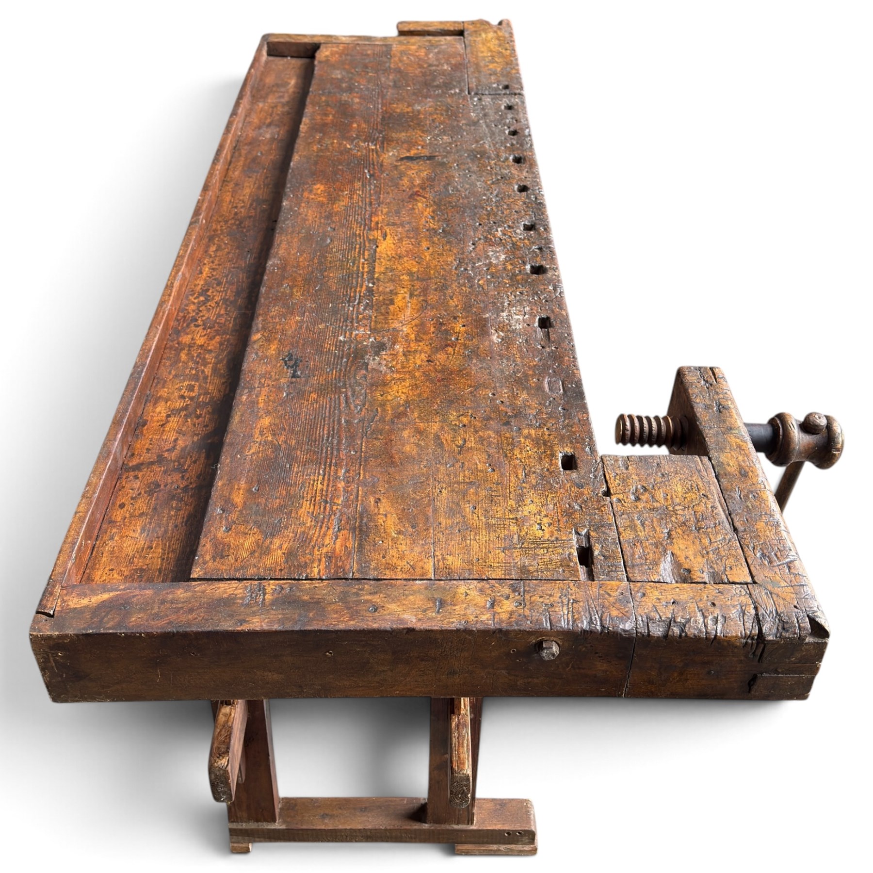 Large early 20th century rustic stained reclaimed pine workbench, the substantial plank top with recessed tool well and two homemade wooden screw vices, above a single frieze drawer and slatted undertier, raised on trestle end supports