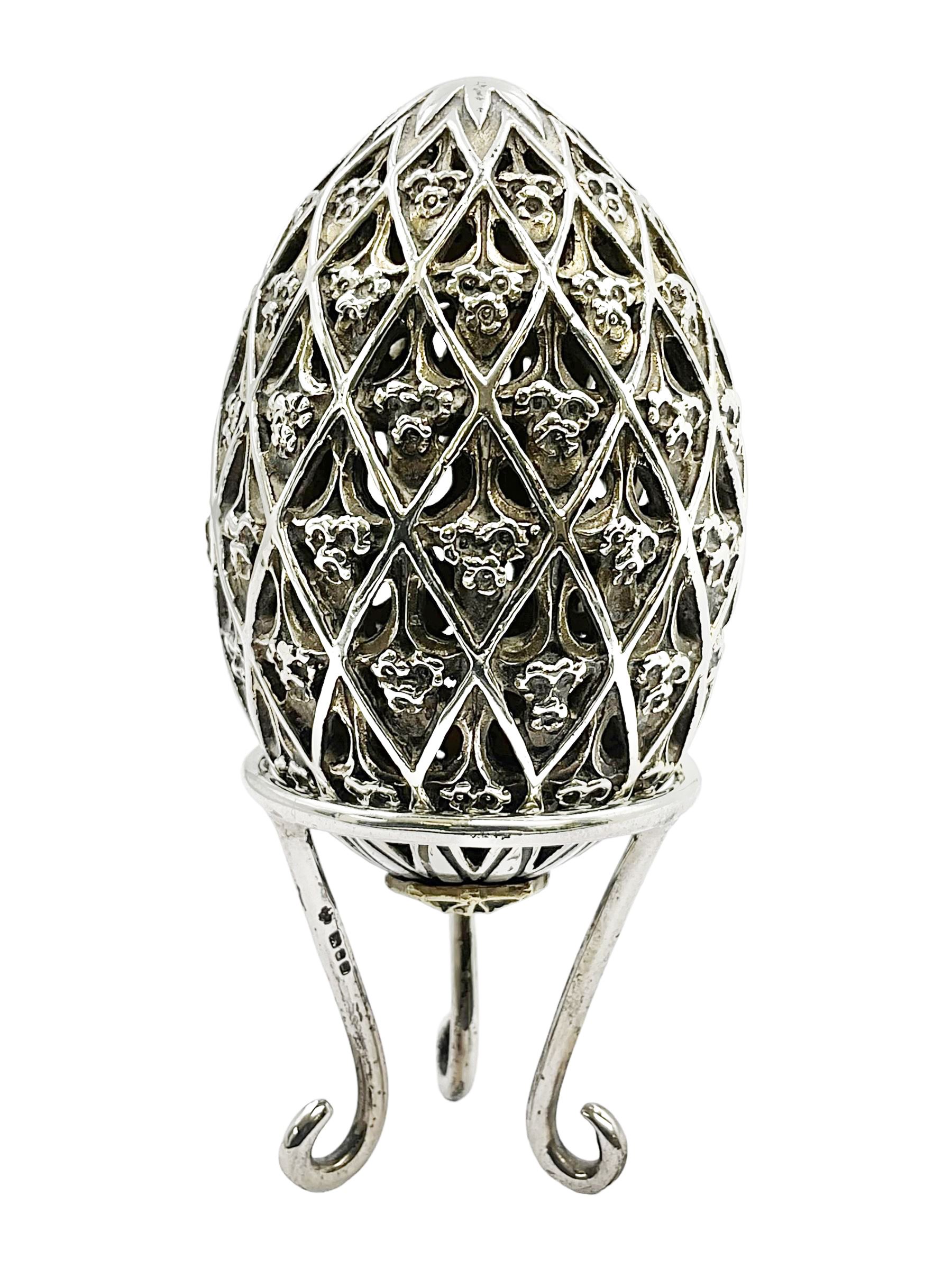 Modern silver limited edition Easter egg, no. 70/500, the openwork lattice body decorated with gilded panels of flower heads, opening to reveal a gilt interior, upon silver stand with three scrolling pad feet, each hallmarked St James House Company, London 1979, height including stand 8cm