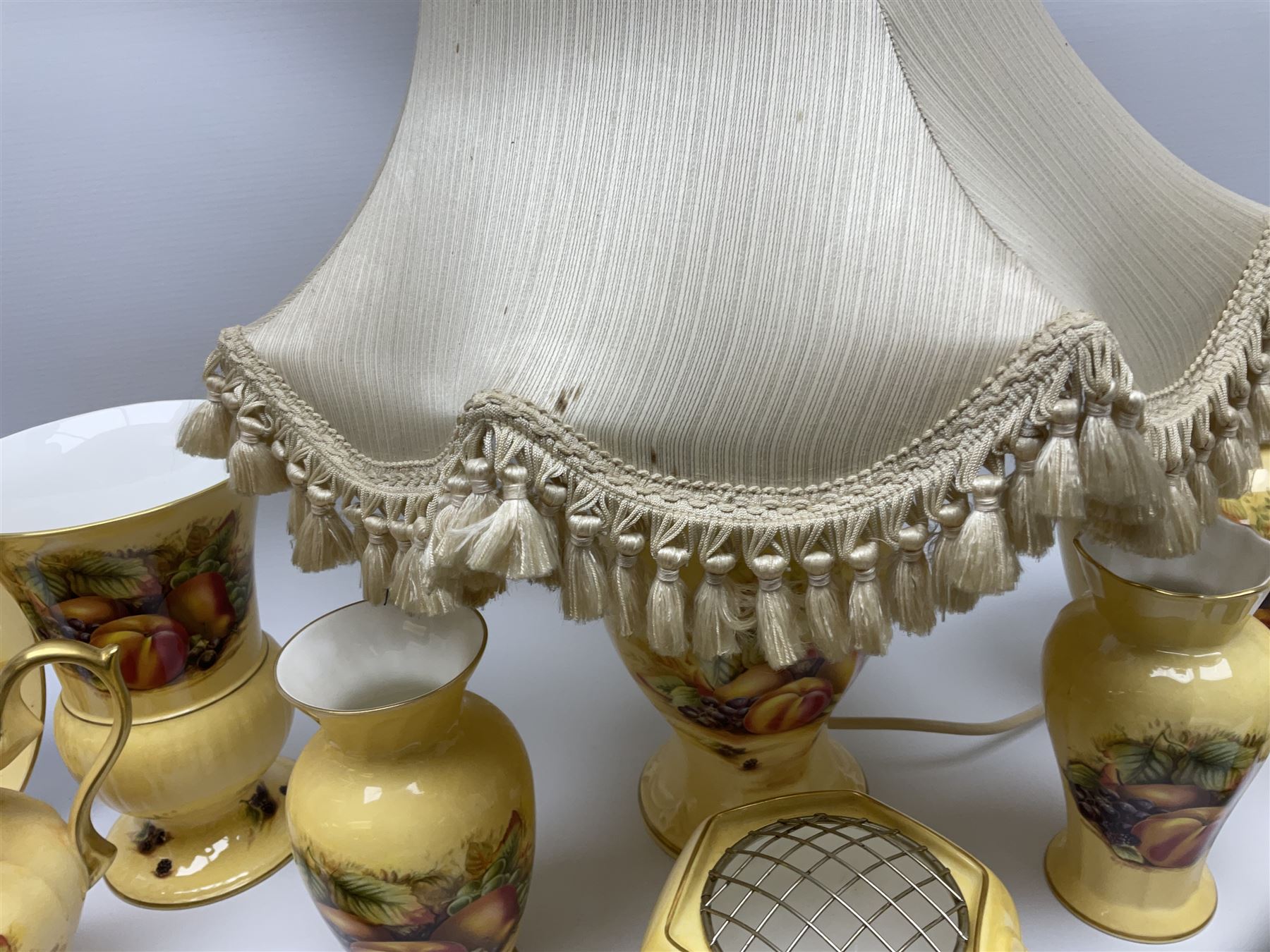 Collection of Aynsley Orchard Gold pattern wares, comprising lamp base, three jars and covers, six vases or various size and form, large jug, lidded dish, pair of cruets, pair of candlesticks, mug, two pin dishes, lobed dish, tea cup, saucer, size plate, and cake plate, and two further cups and saucers, each cup decorated with central Orchard Gold reserve to the interior against a mottled pink or green ground. 