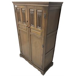 Mid-20th century Jacobean design medium oak double wardrobe or hall cupboard, enclosed by two panelled doors carved with Gothic design tracery 