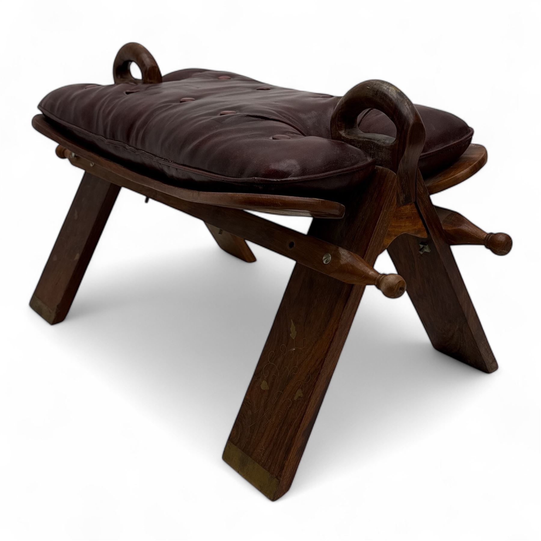 Pair of early 20th century Anglo-Indian camel saddle stools, with deep buttoned red leather upholstered seats and horn-shaped pommels, on X-form supports with turned ball finials