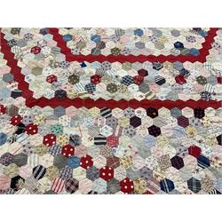 19th century patchwork quilt, hand stitched from hexagons of various materials including printed patterned and floral examples, featuring repeating large central hexagon to centre, the top and bottom with thick panel red jacquard border, the sides bordered with plain red fabric, lined with panels to reverse, 180 x 190 cm
