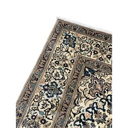 Persian Kashan ivory ground carpet, central rosette medallion surrounded by swirling leafy branches and floral sprays, the main border with scrolling pattern interspersed with floral motifs, within guard stripes 
