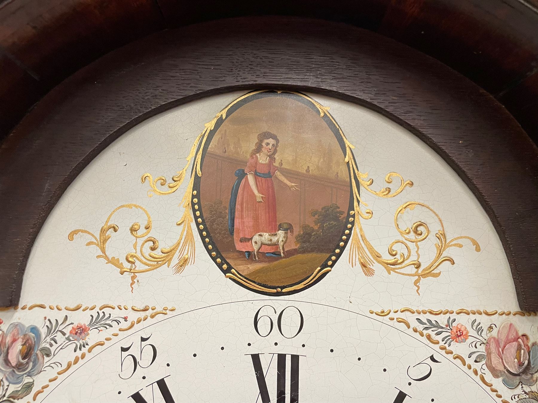 Denton & Fox of Hull – Early 19th century mahogany 8-day longcase clock c1802, pagoda pediment with an oval inlay and three ball and spire finials, break arch painted dial and hood door flanked by reeded pilasters with brass Corinthian capitals, long trunk door with conforming break arch top on a rectangular plinth raised on bracket feet, early Wilson (Birmingham) dial with Roman numerals, five minute Arabic’s and minute dots, subsidiary seconds dial and calendar aperture, with matching steel hands, floral spandrels within raised gesso work and a conforming oval depiction of a young maiden and dog to the break arch, dial pinned via a falseplate to a rack striking movement with a recoil anchor escapement striking the hours on a cast bell. With pendulum and weights.
Joseph Denton was a respected and prolific Hull clock maker working in Scale Lane Hull 1779 and Silver Street 1782-1814. Entering a short-lived partnership with Charles Fox from Beverley in 1802.
