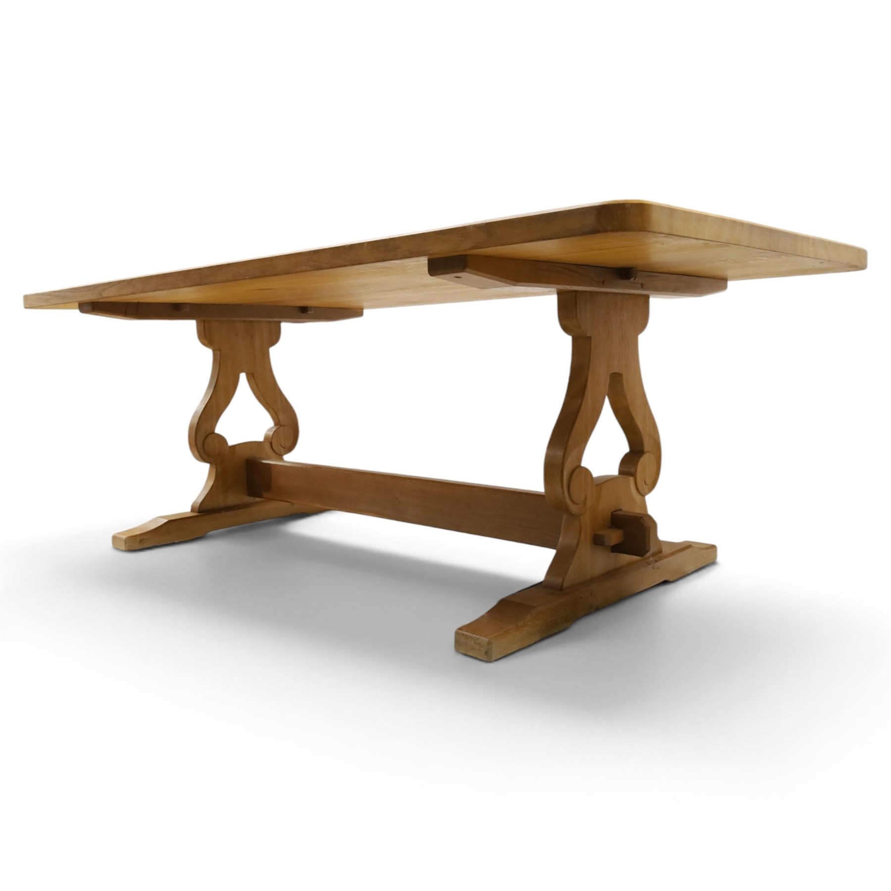 Acorn Industries - oak dining table, rectangular top with rounded corners and chamfered edge, raised on twin lyre-shaped supports united by pegged stretched on sledge feet, carved with acorn signature to stretcher, by Alan Grainger, Brandsby