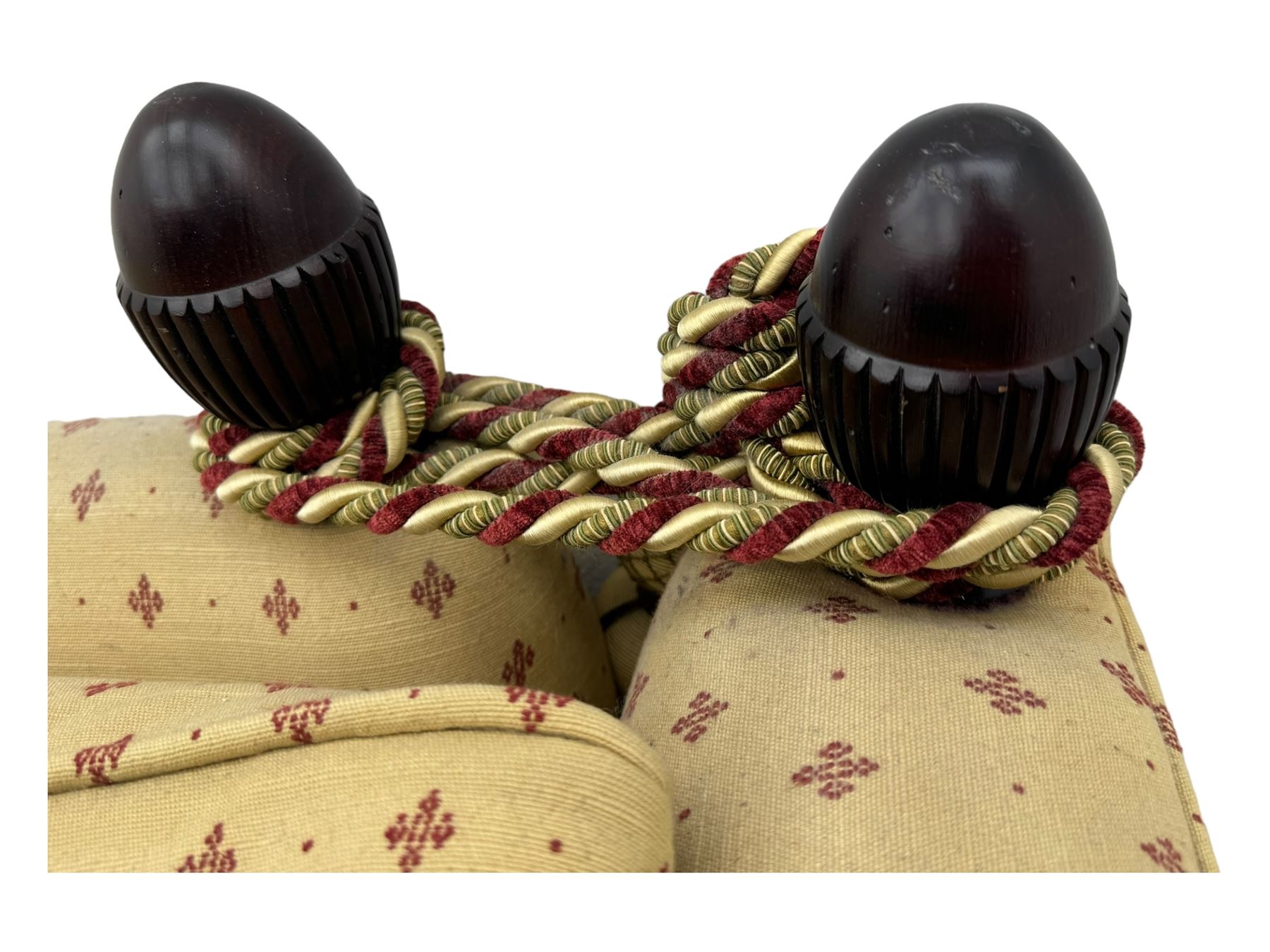 20th century Knole design two seat sofa, high back and double drop-arm joined by mahogany finials and ties, upholstered in camel ground fabric with red lozenge design, on turned supports with brass castors