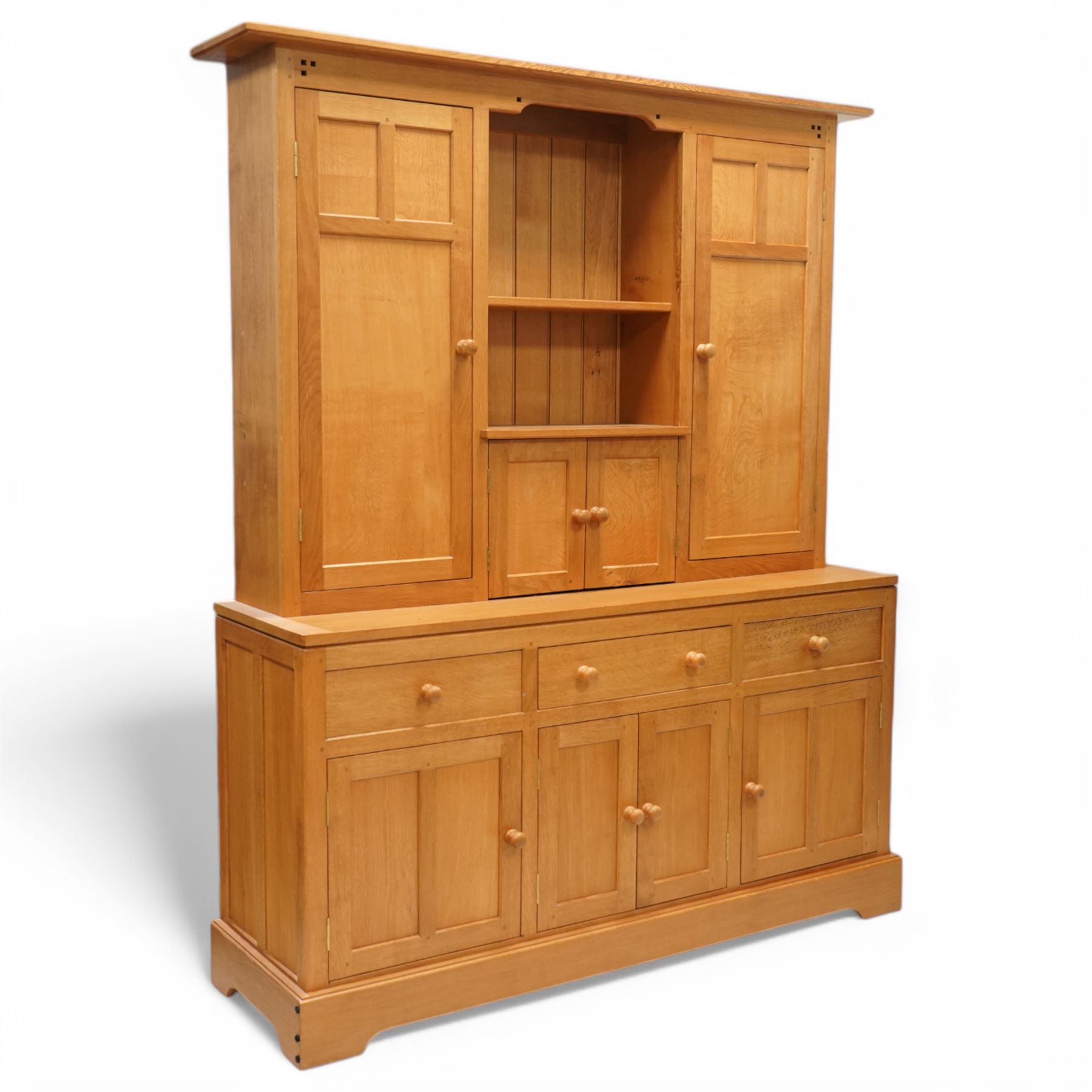 Yorkshire oak dresser, projecting top over open centre fitted with shelf, small double cupboard and flanking full height cupboards, the lower section fitted with three drawers and cupboards, enclosed by panelled doors, on plinth base