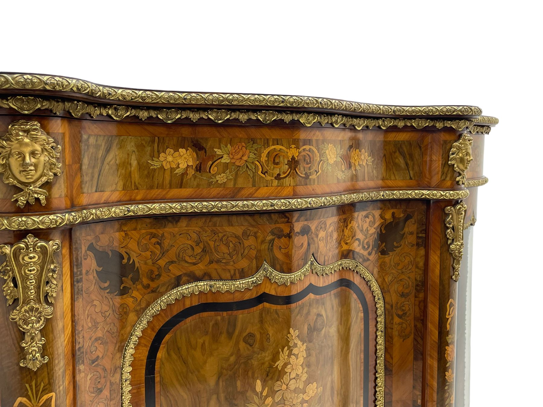 Victorian design inlaid figured walnut credenza sideboard, shaped form with crossbanded and book-matched top, the frieze rails inlaid with foliage scrolls and flower heads, central panelled door inlaid with floral urn flanked by two glazed doors, on shaped plinth base inlaid with foliate decoration, mounted by cast gilt metal masks and floral egg and dart beading 