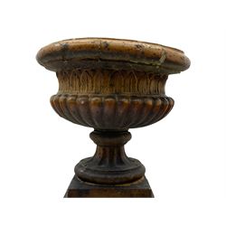 Victorian salt glazed terracotta garden urn on plinth, the Campana shaped urn with foliate decoration over gadrooned underbelly, the plinth of square tapering form, each side with recessed moulded archway decorated with urn cartouches, stepped and moulded skirt base