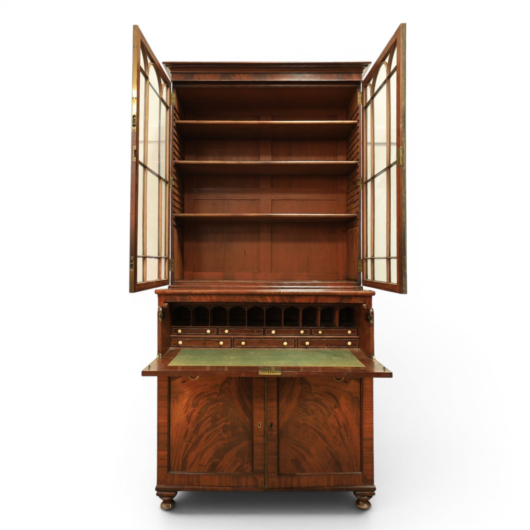 Early 19th century mahogany secretaire-bookcase, projecting cornice above astragal glazed cabinet with adjustable shelved interior, fall front secretaire drawer, fitted interior with pigeonholes and drawers, flame mahogany fronted cabinet with three drawers, on turned supports 