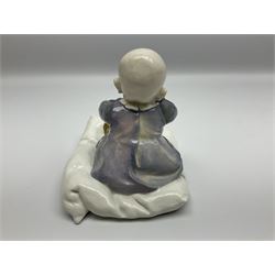Early 20th century Meissen figure, circa 1905-1924, designed by Konrad Hentschel, modelled as a baby seated upon a cushion wearing a merging purple and blue dress, green and white striped leggings and brown shoes, with blue crossed swords mark and incised model number U 150 beneath, H12.5cm

