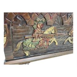 Mid-20th century carved hardwood chest, the rectangular hinged top with decorative strap hinges, the front and sides deeply carved with medieval-style jousting knights, heraldic shields, and architectural elements, raised on shaped block feet