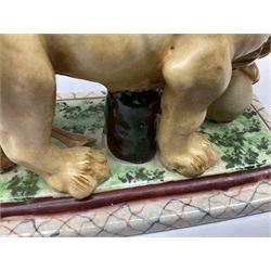 19th century Staffordshire style figure of a lion, modelled with paw resting upon globe, upon a naturalistically modelled rectangular base with canted corners and decorative border, L19cm