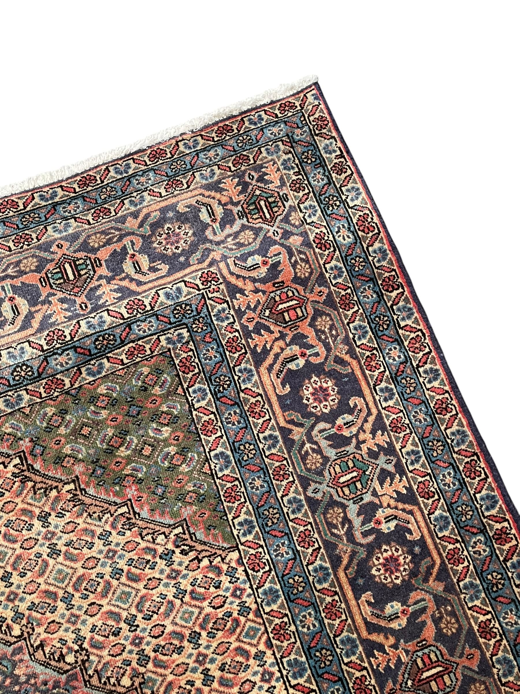 Persian Bidjar peach ground carpet, central pole medallion enclosed within lozenge field and spandrels, decorated all over with small Heratti motifs, the main border with trailing pattern decorated with stylised plant and Boteh motifs, within two triple band guard stripes with repeating flower head decoration 