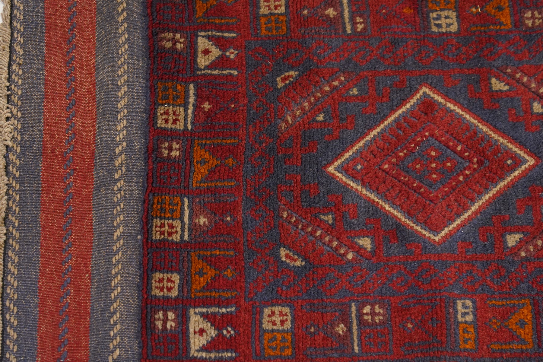 Near pair of Afghan Meshwani runner rugs, each with four red lozenge medallions on a blue ground interspersed with hooked geometric motifs, enclosed by patterned red borders, striped kilim end panels (2)