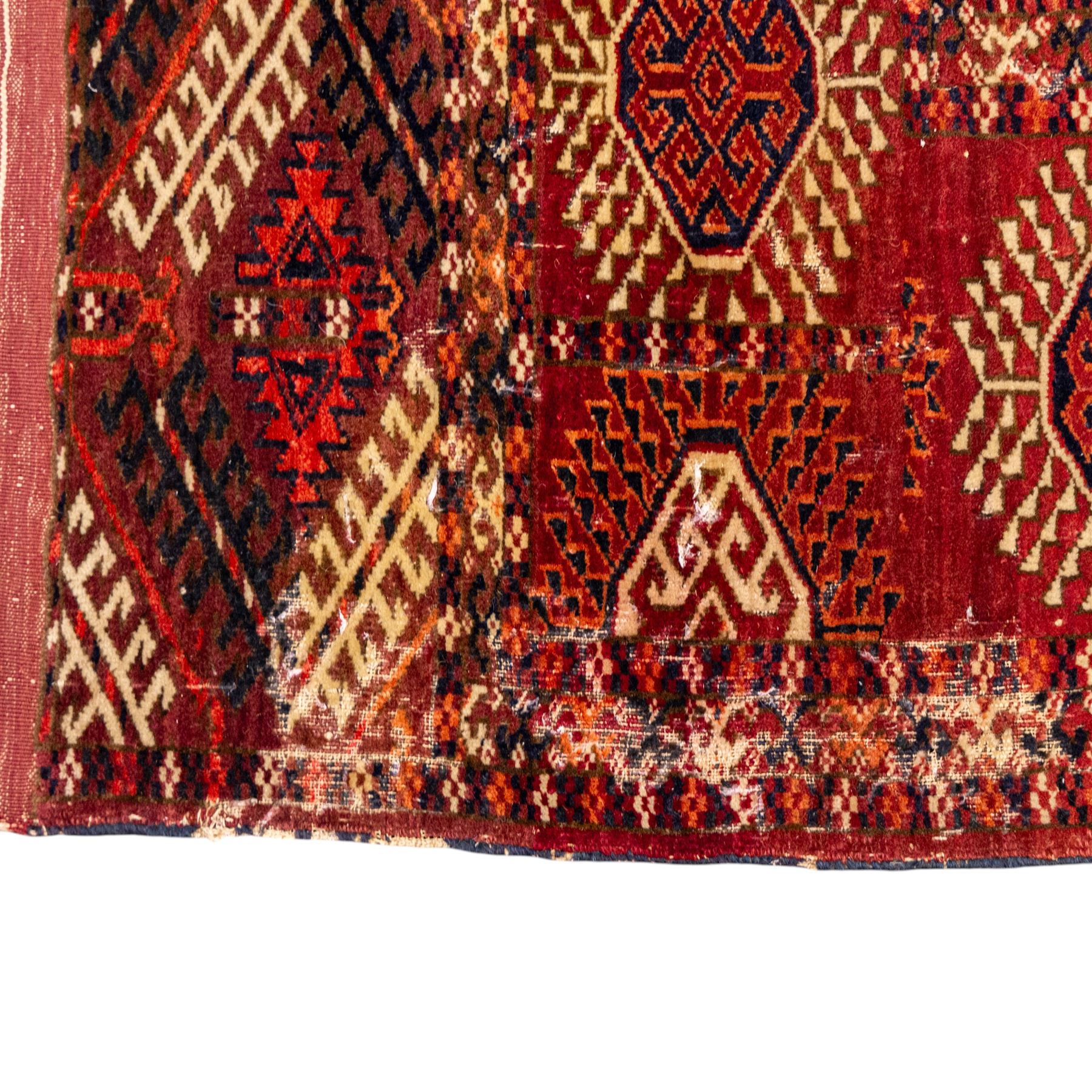 Vintage Bokhara hand-knotted rug, madder field woven in rows of octagonal Tekke guls arranged in vertical columns, each enclosing angular cruciform devices and tribal motifs, divided by narrow indigo lines, within multiple geometric borders incorporating stepped lozenges and latch hook devices, with cotton fringe ends 