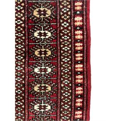 Persian Bokhara rug, red ground and decorated with single row of Gul motifs, multiple band border with geometric design
