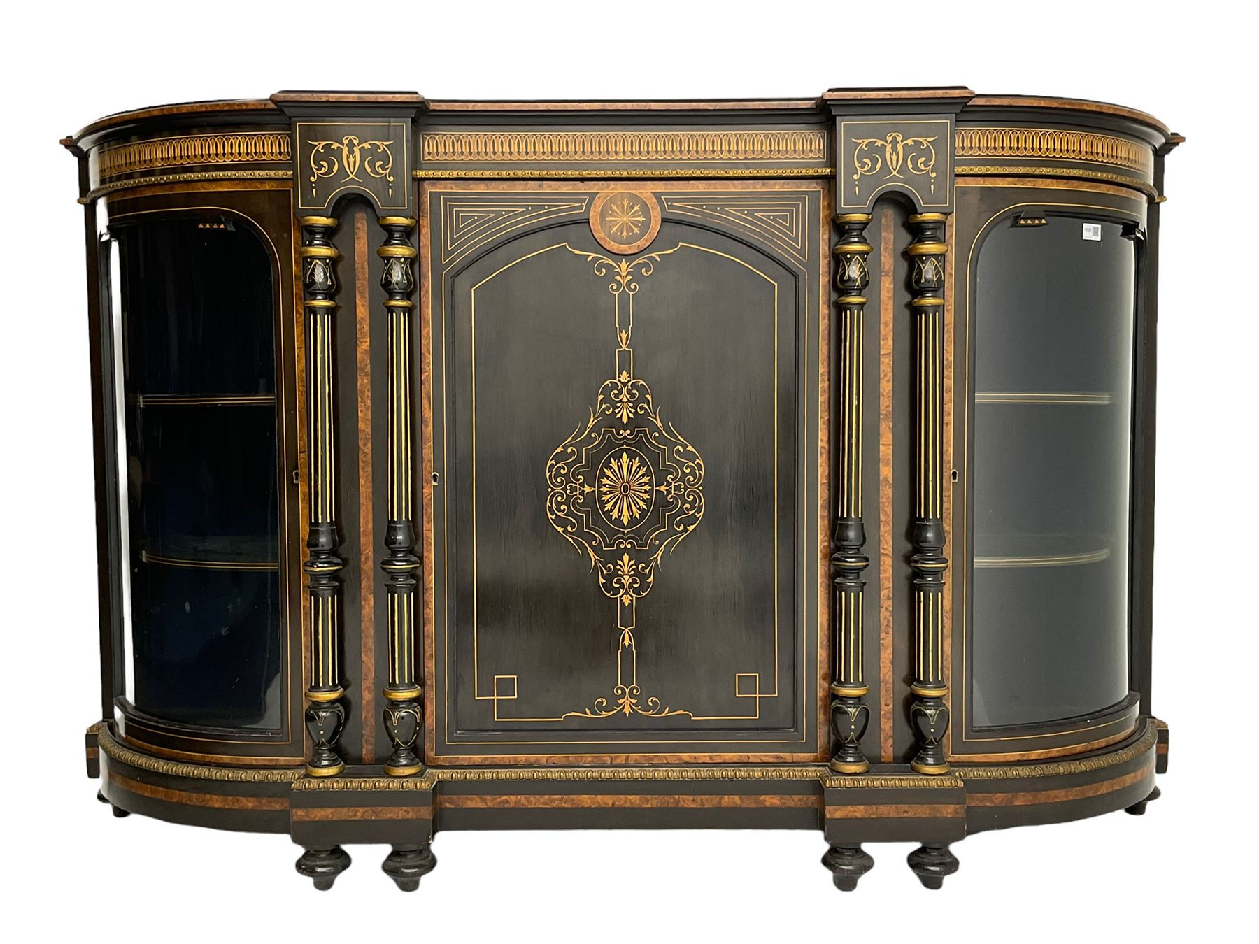 Victorian ebonised and inlaid credenza, break-front with curved ends, the front fitted with two curved glazed doors and central panelled door, inlaid with scrolling foliate and star motifs, quadruple turned and fluted pilasters to front, gilt egg and dart moulded edge on plinth base with figured walnut band, on turned feet