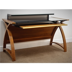  Contemporary walnut finish bent plywood desk with black glass top and keyboard slide, W130cm, H83cm, D61cm  