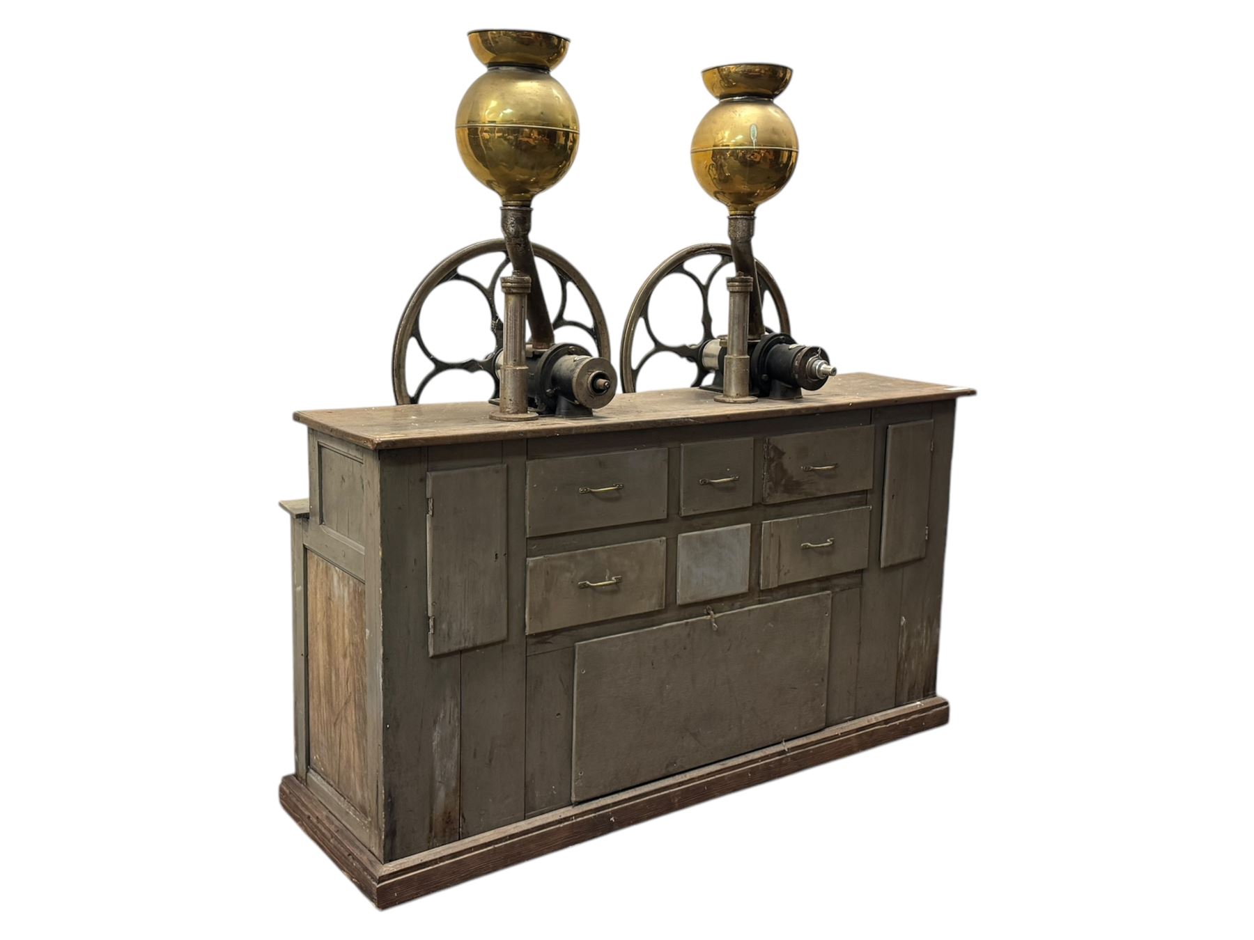 Cabinet with multiple drawers and cupboards mounted with two industrial coffee grinders with large flywheels and brass coffee reservoirs, early 20th century 
