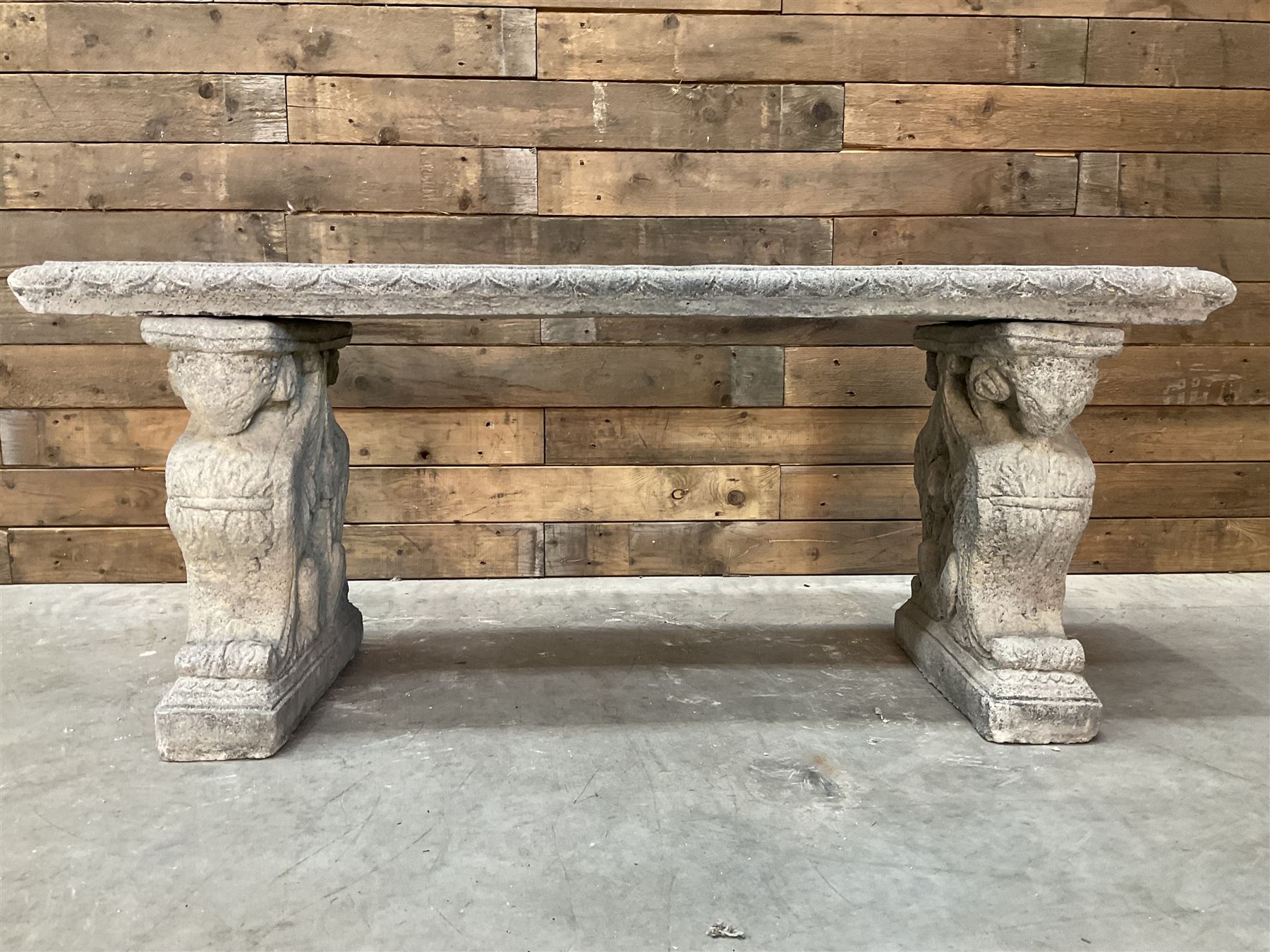 Cast stone garden Rams Head bench, two pillars set with architectural rams heads, rectangular slab seat