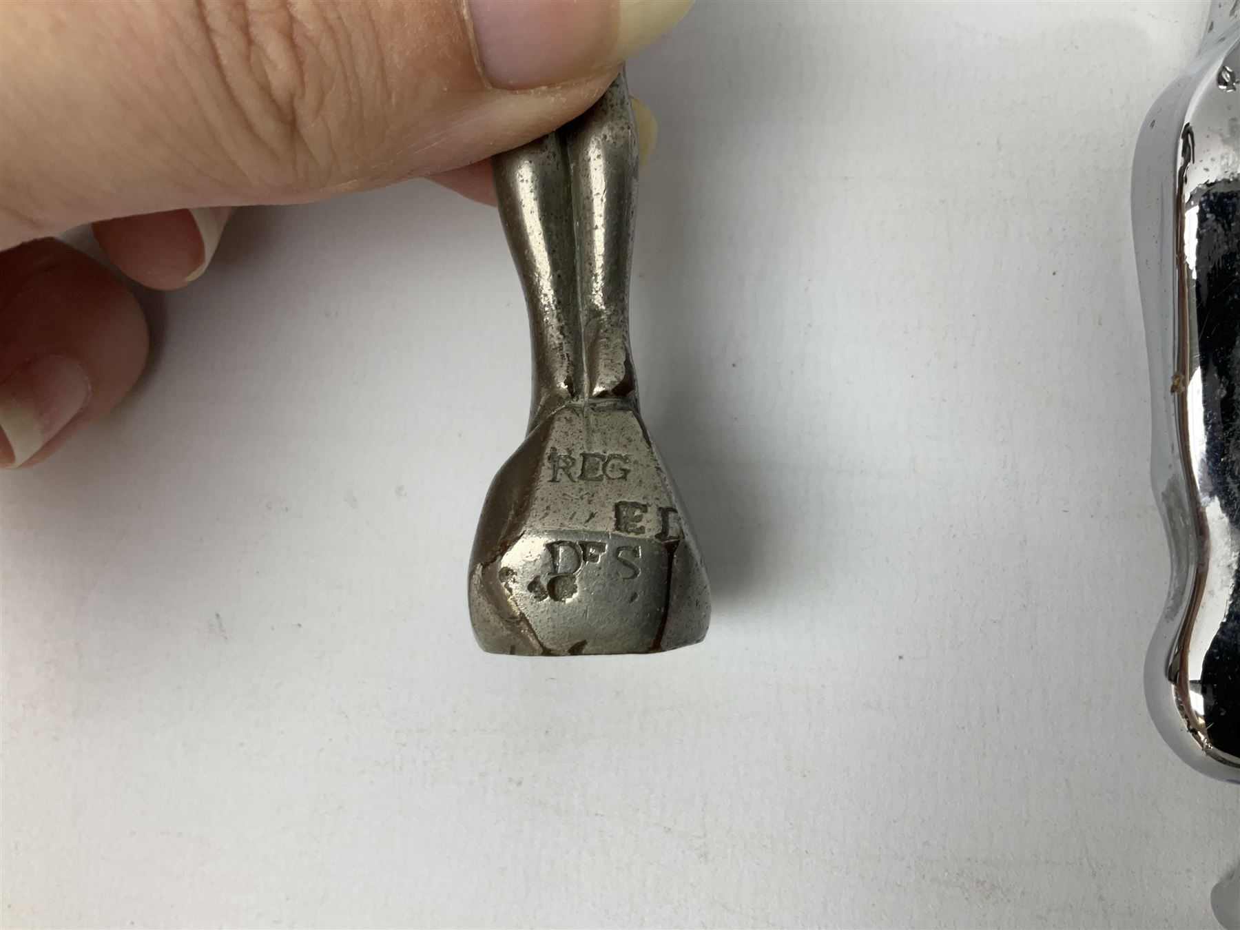 Nickel plated car mascot as a nude lady in a diving pose, similar to an A.E. Lejeune 'Speed Nymph', but marked 'N.L.C. Co. RegEd Des.'; chrome leaping Jaguar car mascot; and quantity of car model name letters, numbers and logos including Mercedes-Benz etc