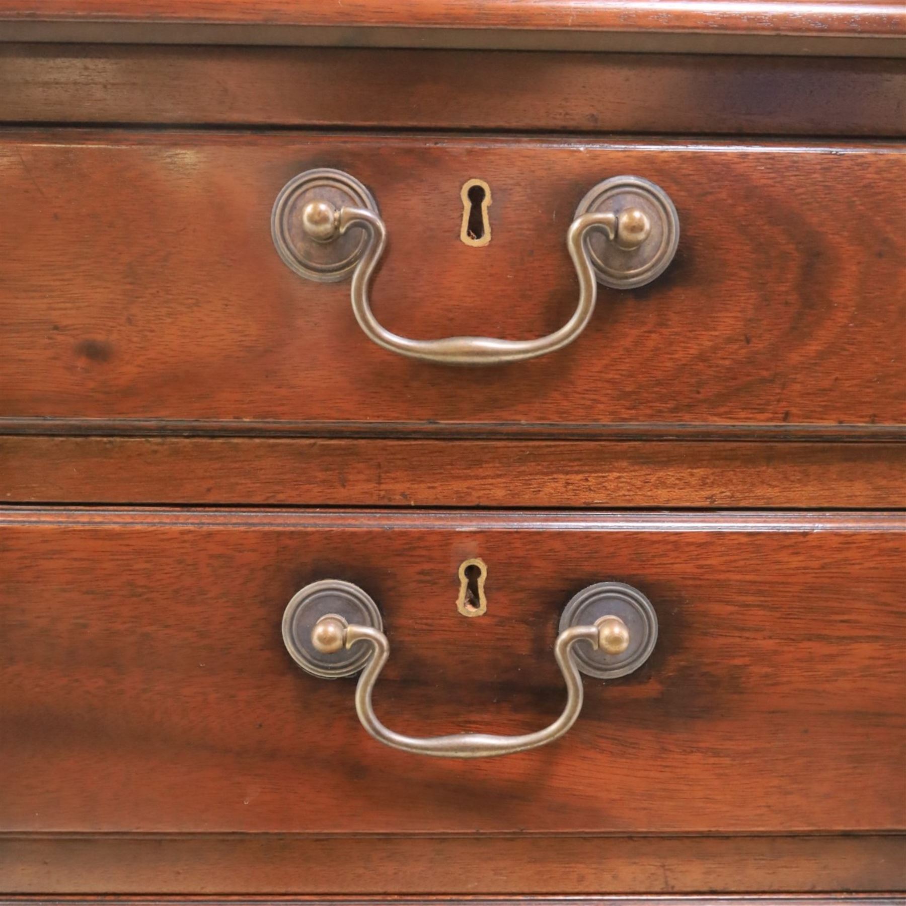 George III style large mahogany reverse breakfront partners desk, red tooled leather writing surfaces crossbanded and moulded edges, flanked by ring-turned cluster columns three frieze drawers with brass swan neck handles, raised on large pedestals with faux drawer fronted cupboard and three graduated drawers, supported on carved ogee feet decorated with C-scrolled and acanthus leaves