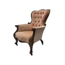Victorian walnut framed armchair, shaped back with carved and scrolled arm terminals, upholstered in buttoned pale pink fabric, raised on cabriole supports terminating in castors