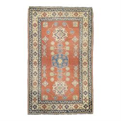 Persian Kazak vermillion ground rug, decorated with a foliate pole medallion with surround...