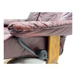 Ekornes Stressless, swivel armchair upholstered in red leather, with matching footstool supported on Oak bases