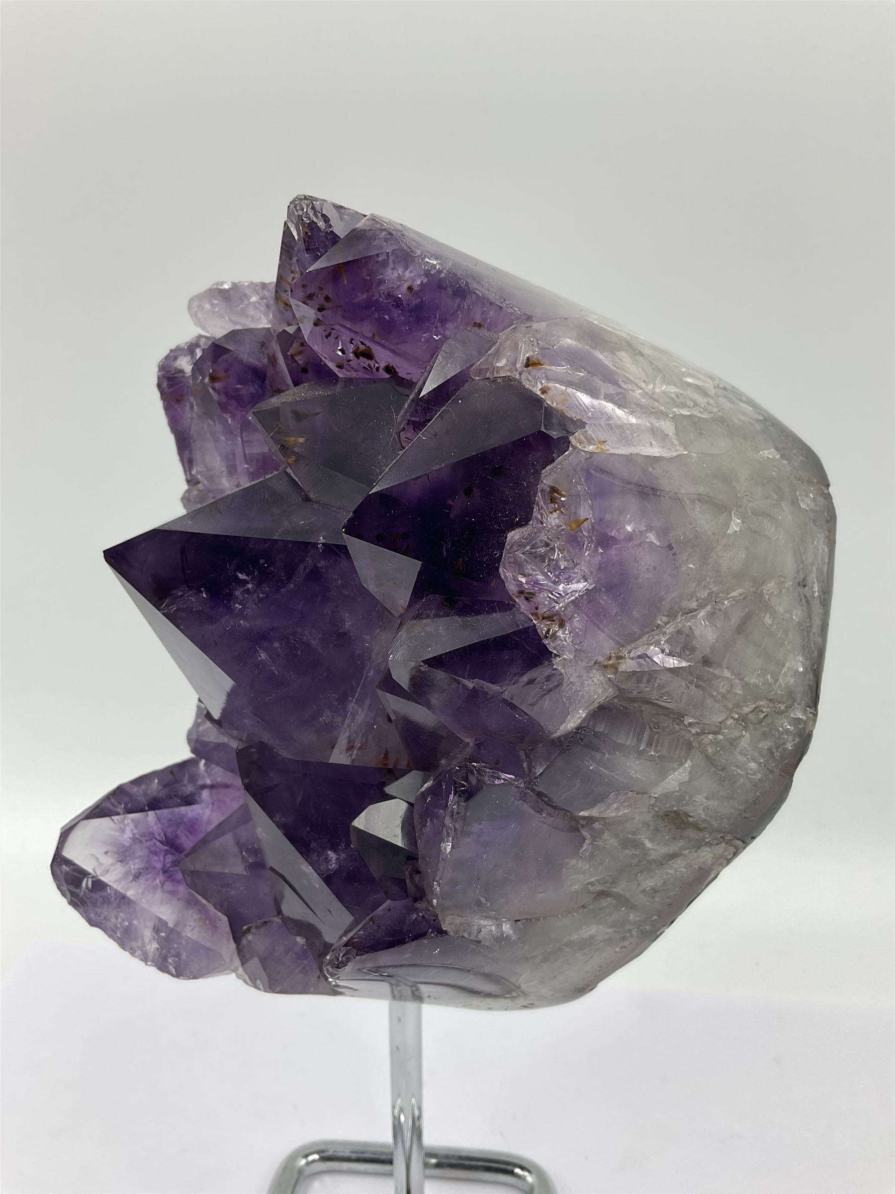 Amethyst crystal geode cluster, with large well-defined crystals, upon a metal stand, H21cm