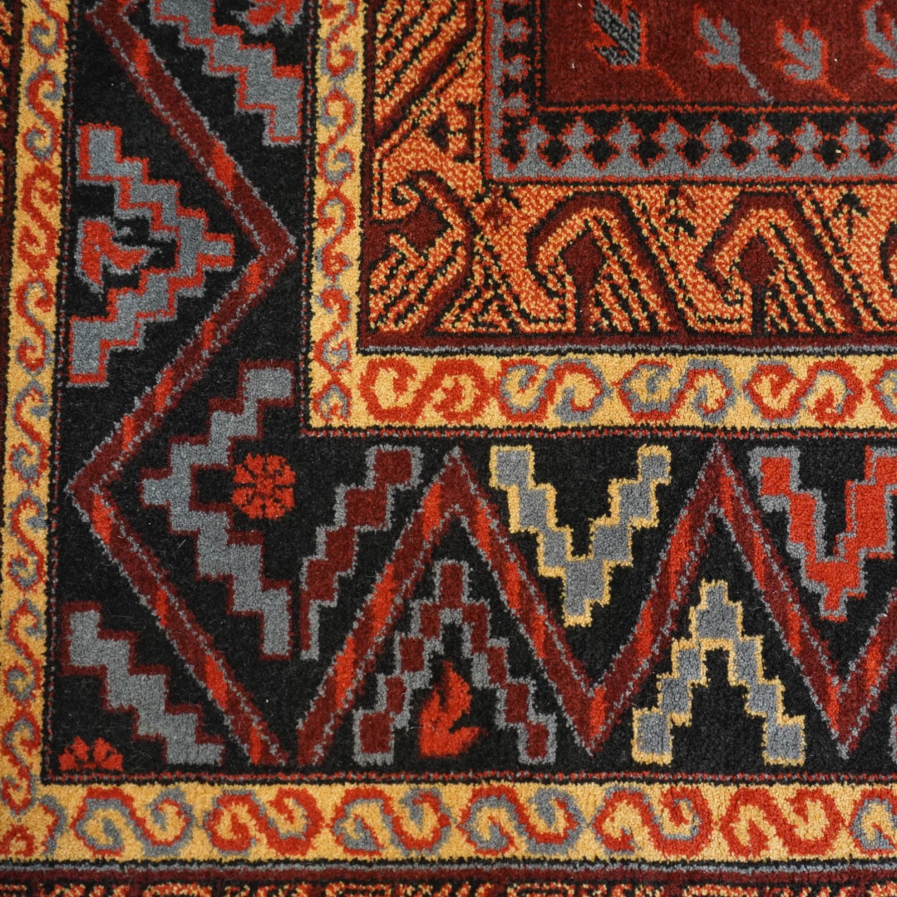 Persian Karabagh design rug, red madder field with three linked octagonal medallions surrounded by floral geometric motifs within multiple stylized borders 