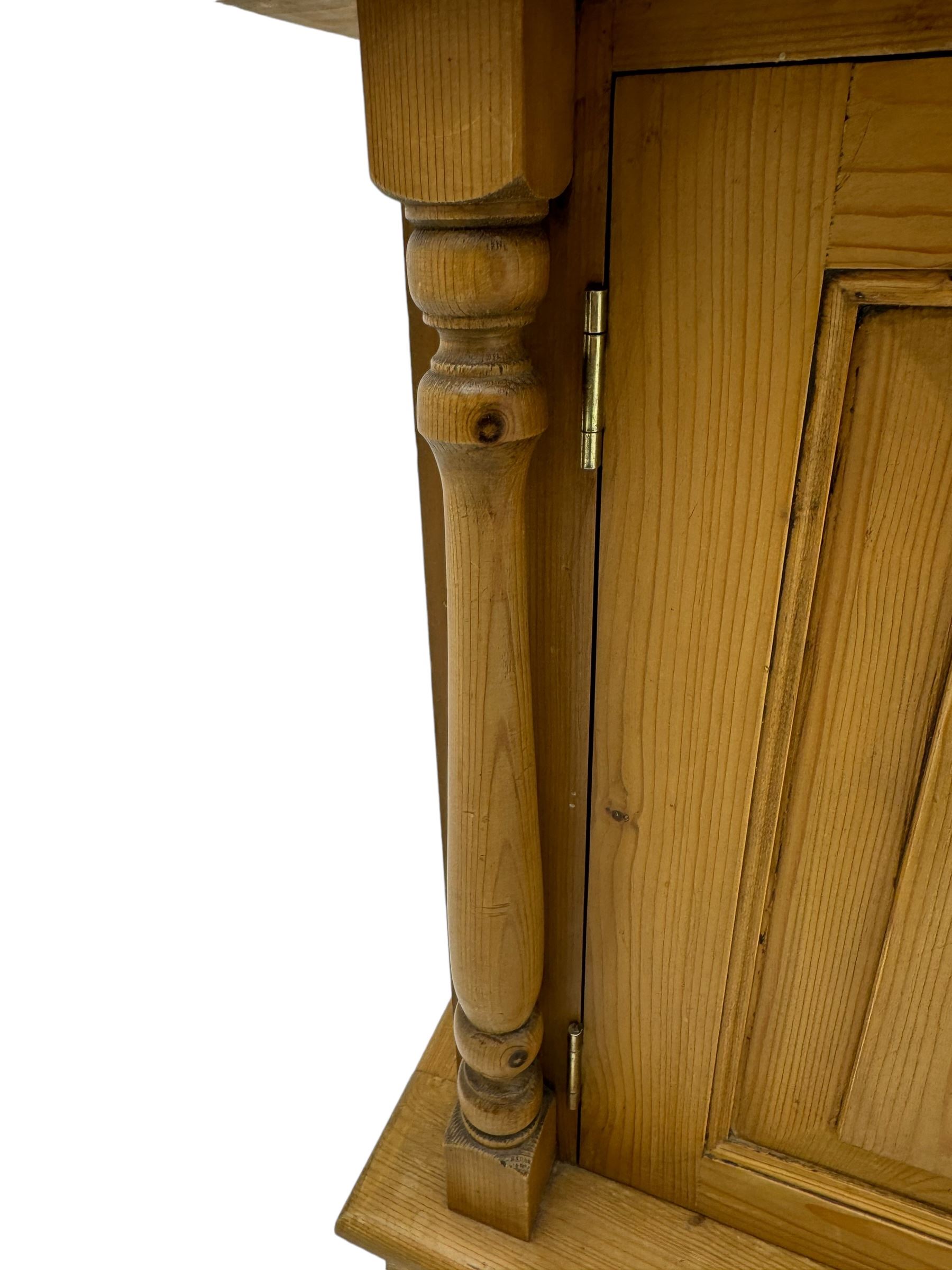 Early 20th century pine kitchen dresser, featuring a hutch with arched top over three open shelves, the base with five drawers over three cupboard doors, turned column supports flanking the doors, scalloped apron base with bracket feet