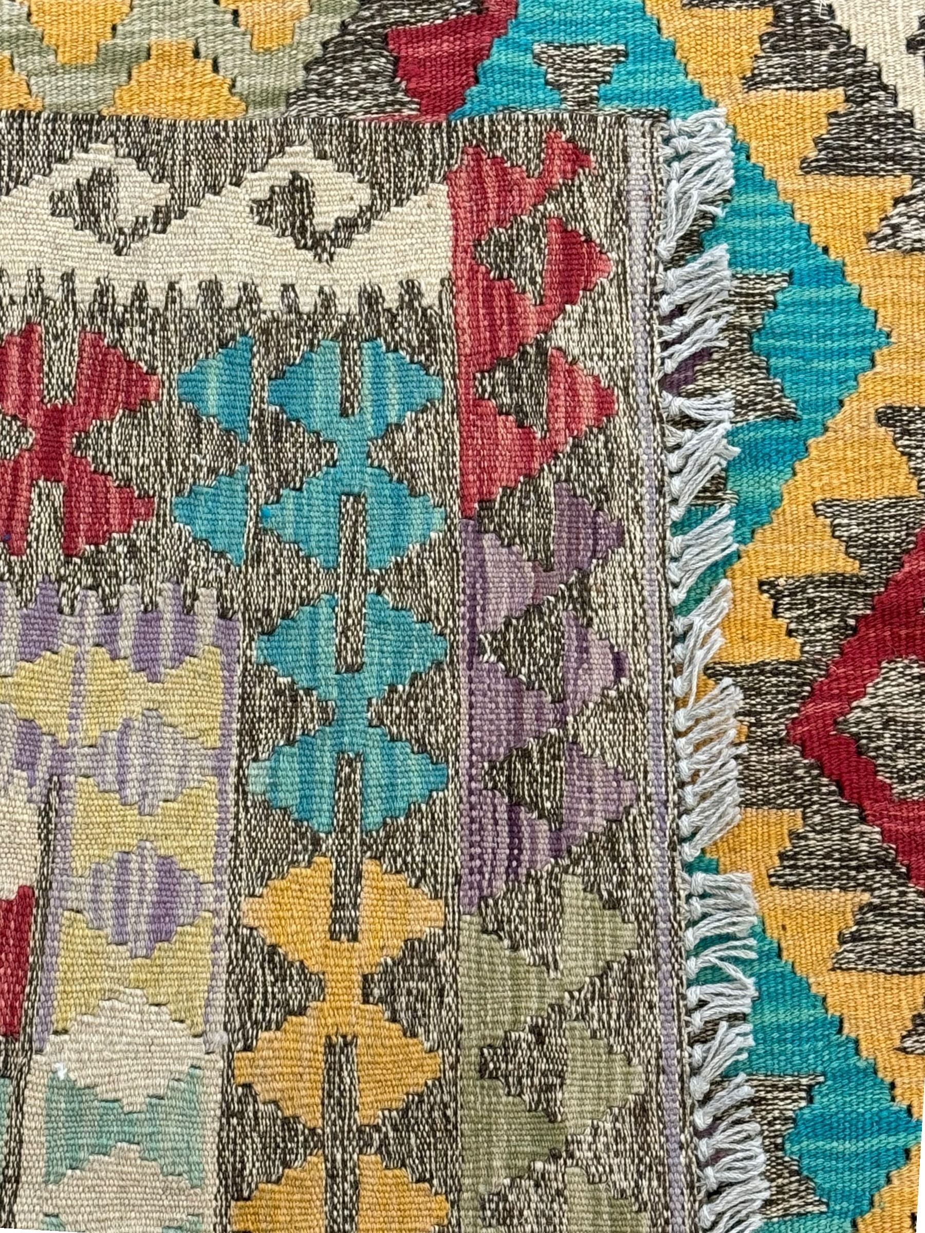 Anatolian Kilim cream ground rug, decorated with repeating diamond motifs in red, blue, yellow, and green, bordered by narrow bands of stylised geometric patterns in contrasting shades