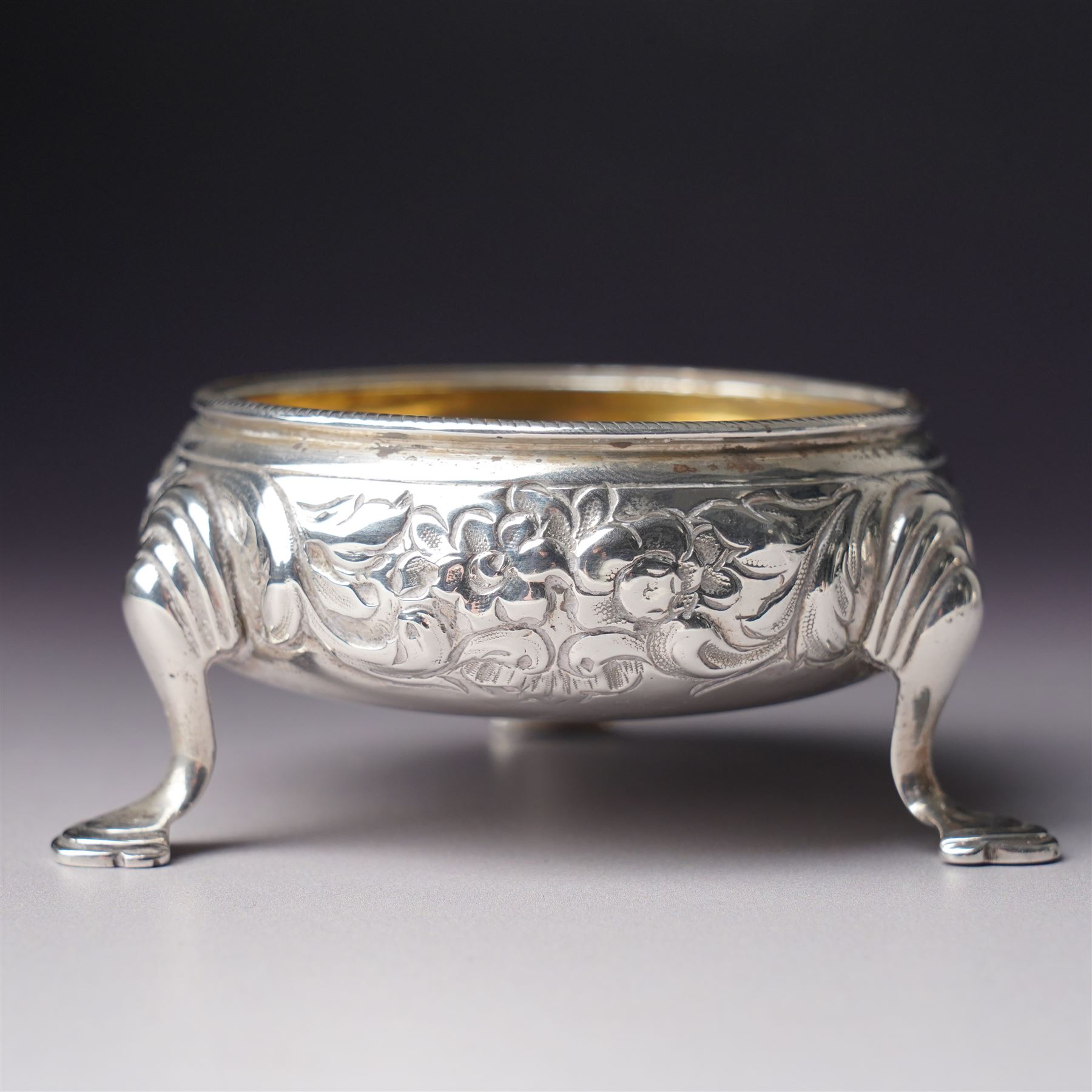 Pair of George III silver circular salts with gilded interiors and embossed decoration and two 19th century condiment spoons, one by Peter and Ann Bateman 