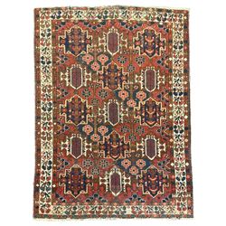 Persian crimson ground rug, the field decorated with three rows of stylised plant medallions and small flowerhead motifs, repeating floral design border with guards 